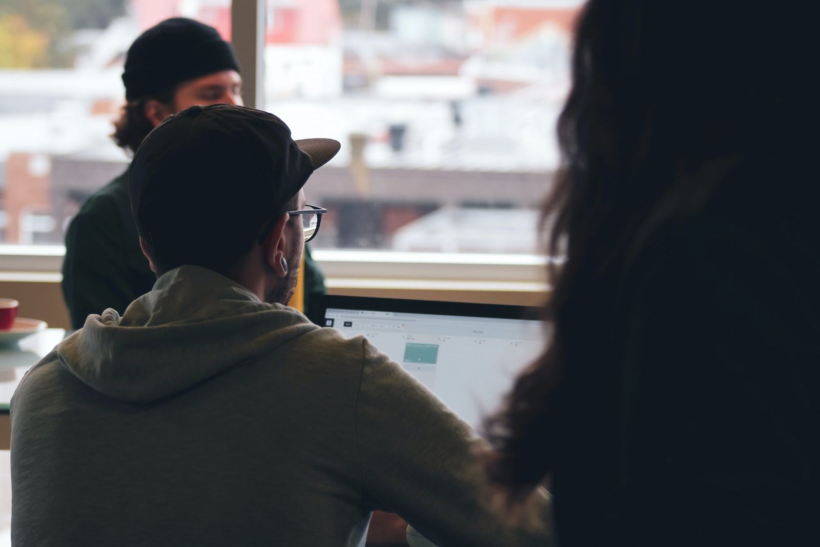 Over a developer’s shoulder, a plain web app open on a laptop beside a bright window